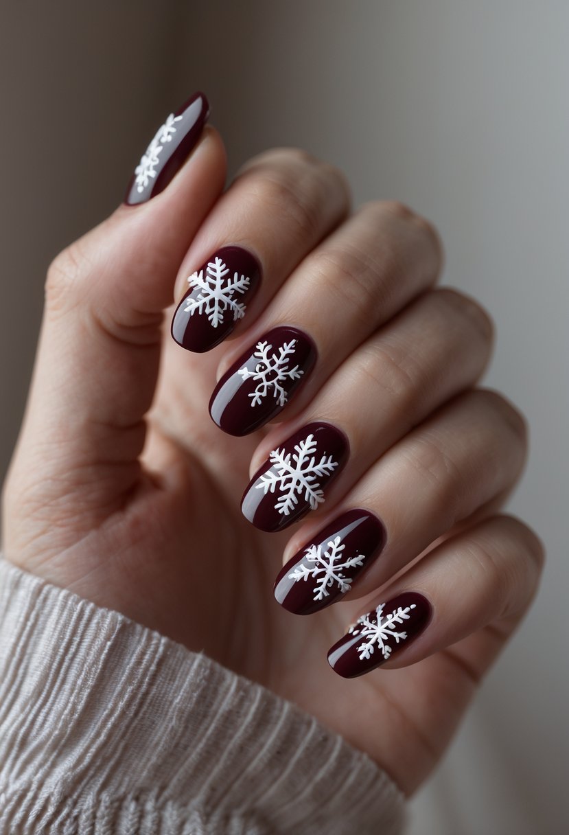 Close-up of a hand with deep burgundy nails decorated with white snowflake designs.