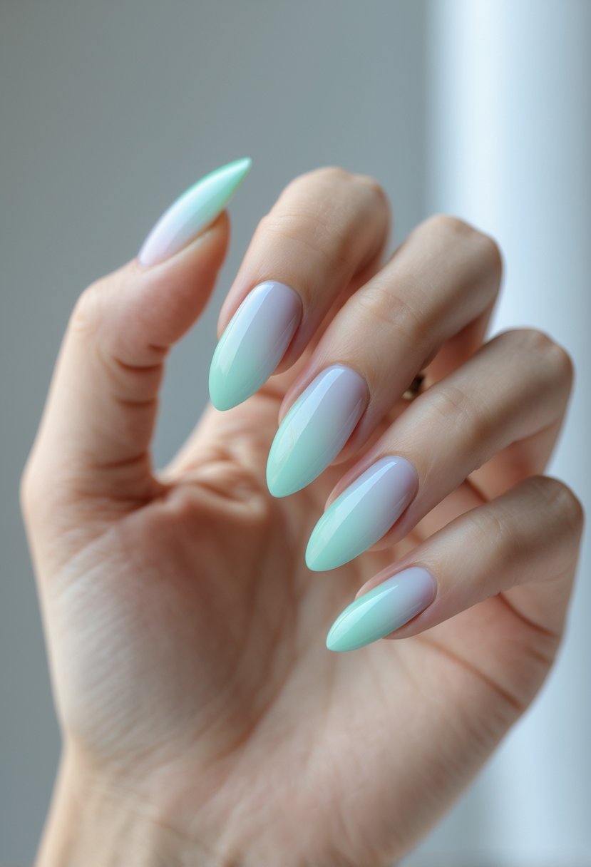 Close-up of a hand with nails painted in a smooth gradient from pastel blue to mint green.