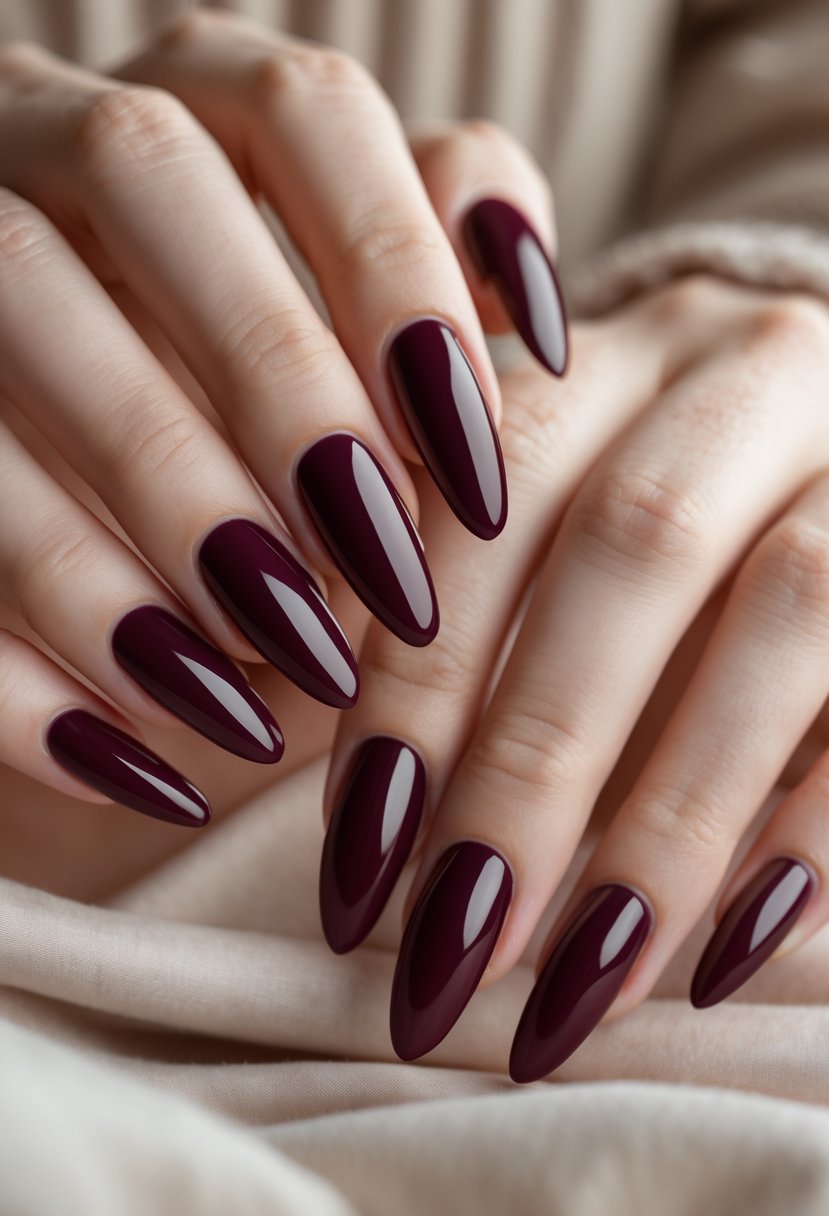 Close-up of both hands with glossy deep burgundy painted nails against a neutral background.
