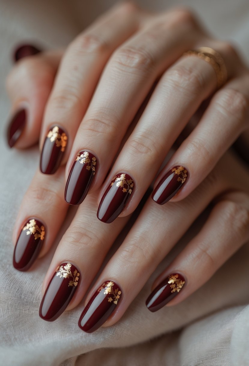 Close-up of hands with warm burgundy ombre nails accented with gold foil.