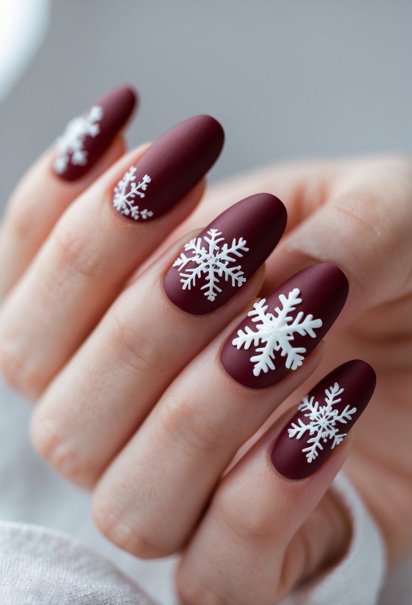 Close-up of a hand with red matte nails featuring glossy white snowflake designs.