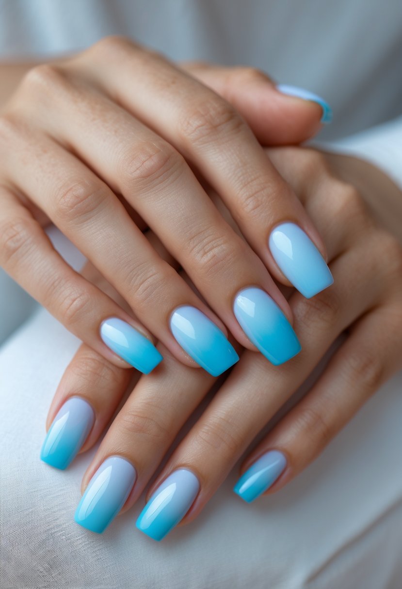 Close-up of hands with light blue ombre nails gently clasped together.