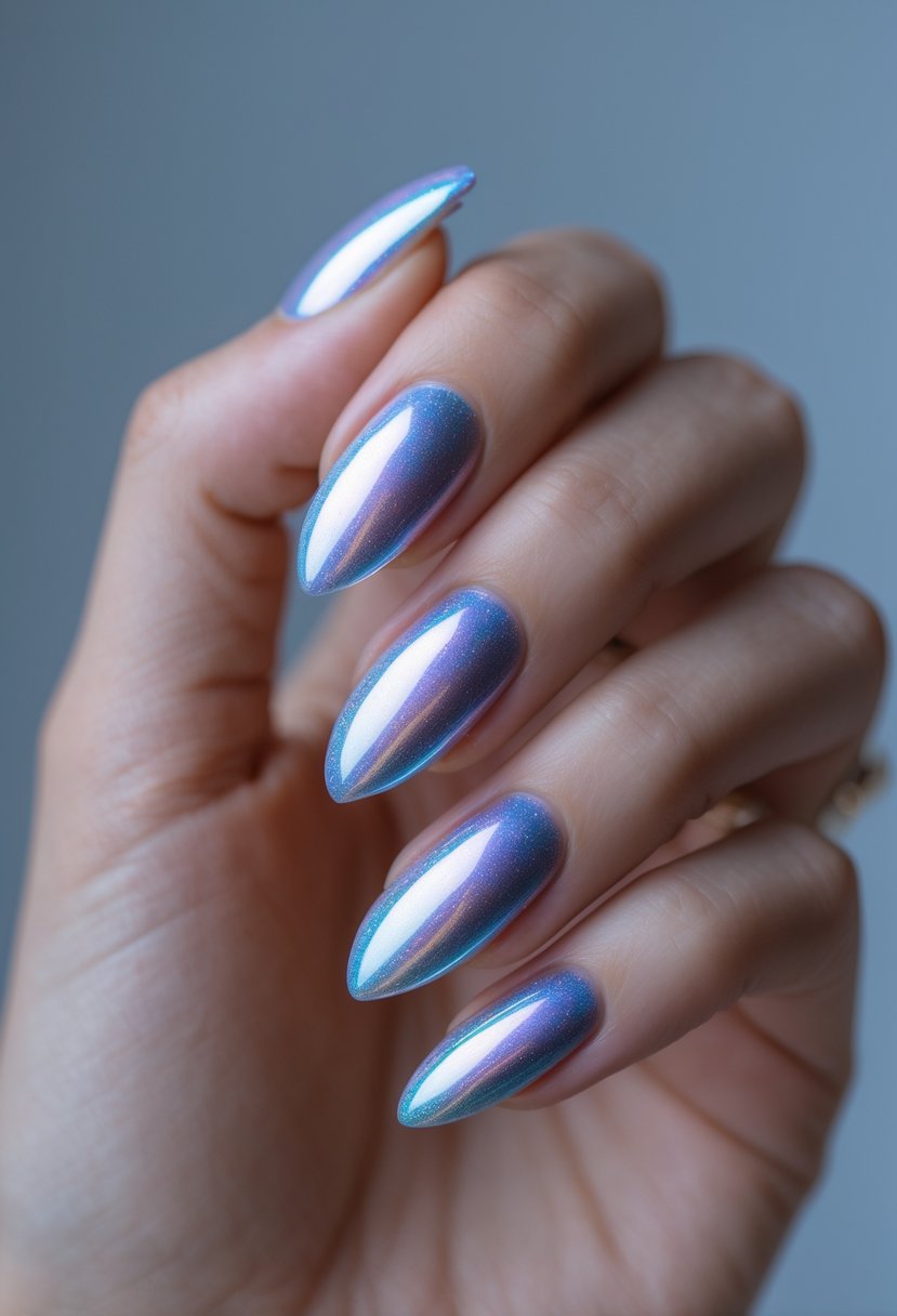 Close-up of a hand with almond-shaped nails painted in shiny iridescent chrome polish showing colors of silver, blue, and purple.
