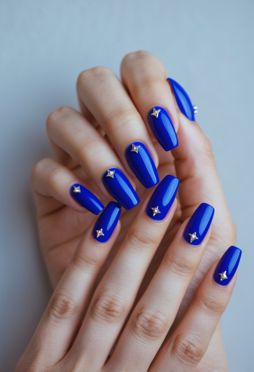 Close-up of hands with royal blue nails decorated with small silver studs.