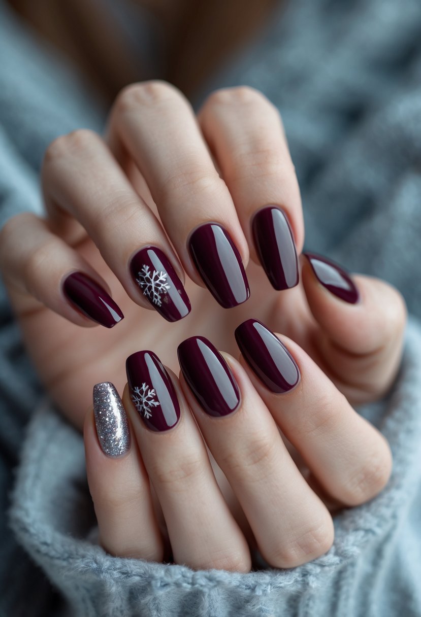 Close-up of hands with burgundy red winter-themed manicured nails against a soft neutral background.