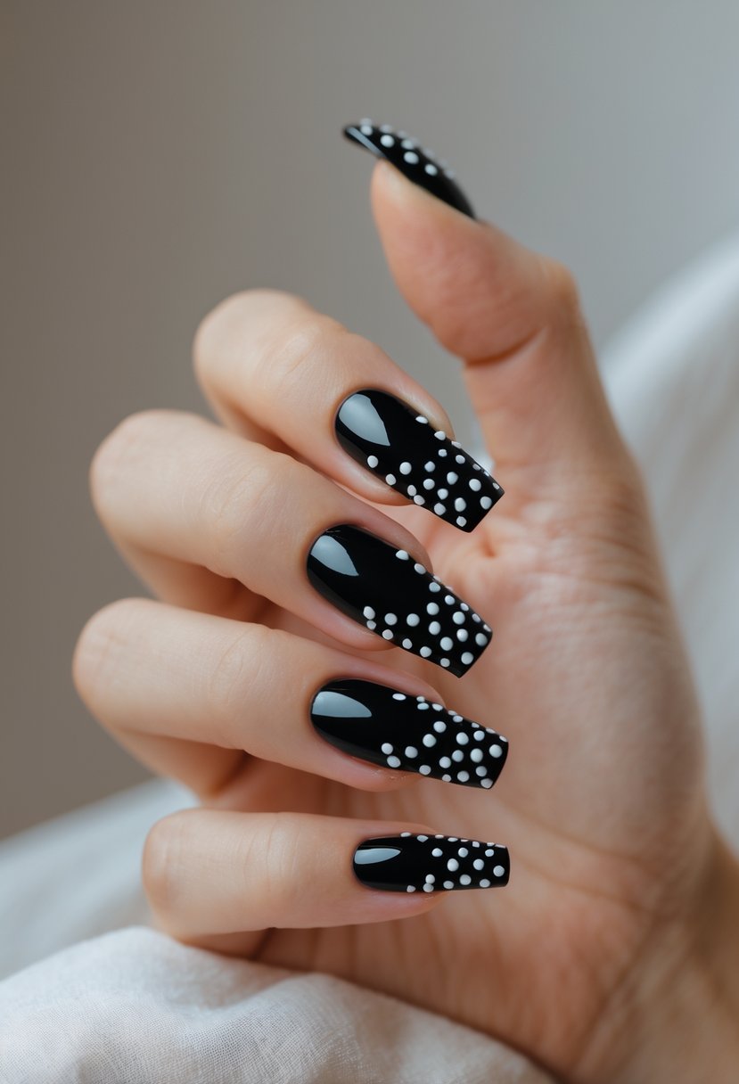 Close-up of a hand with glossy black acrylic nails decorated with small white dots.