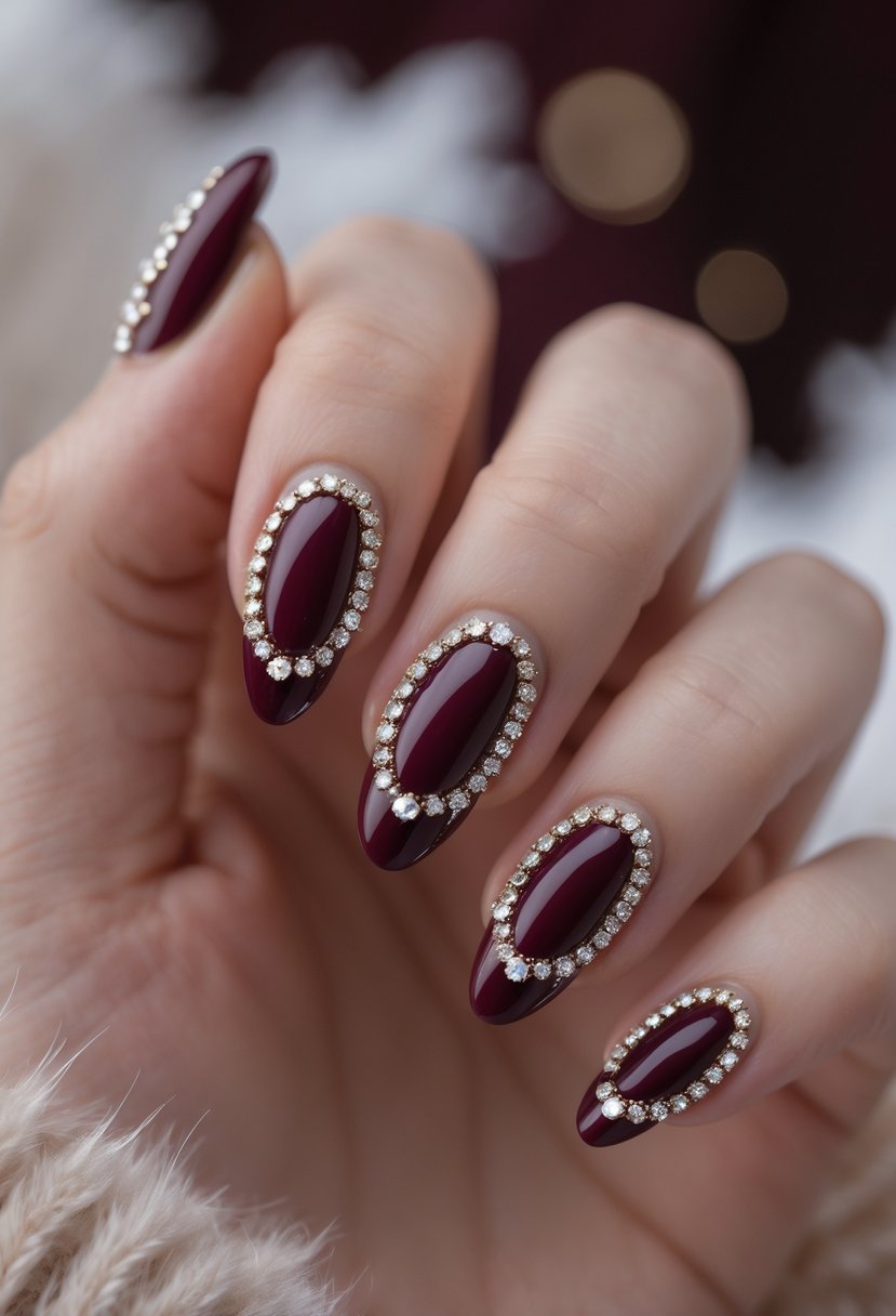 Close-up of a hand with burgundy nails decorated with rhinestones against a blurred dark background.