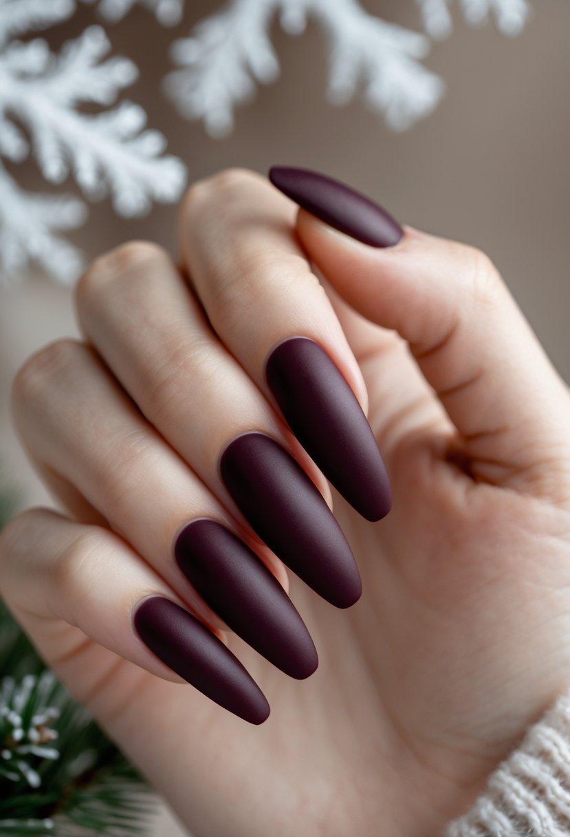 Close-up of hands with deep burgundy matte nails against a soft winter-themed background.