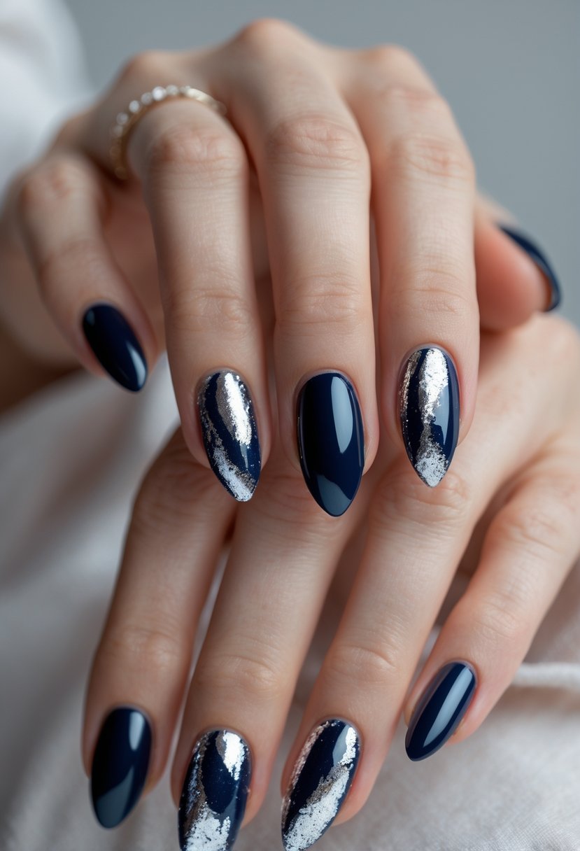 Close-up of hands with dark navy blue nails decorated with metallic silver foil accents.